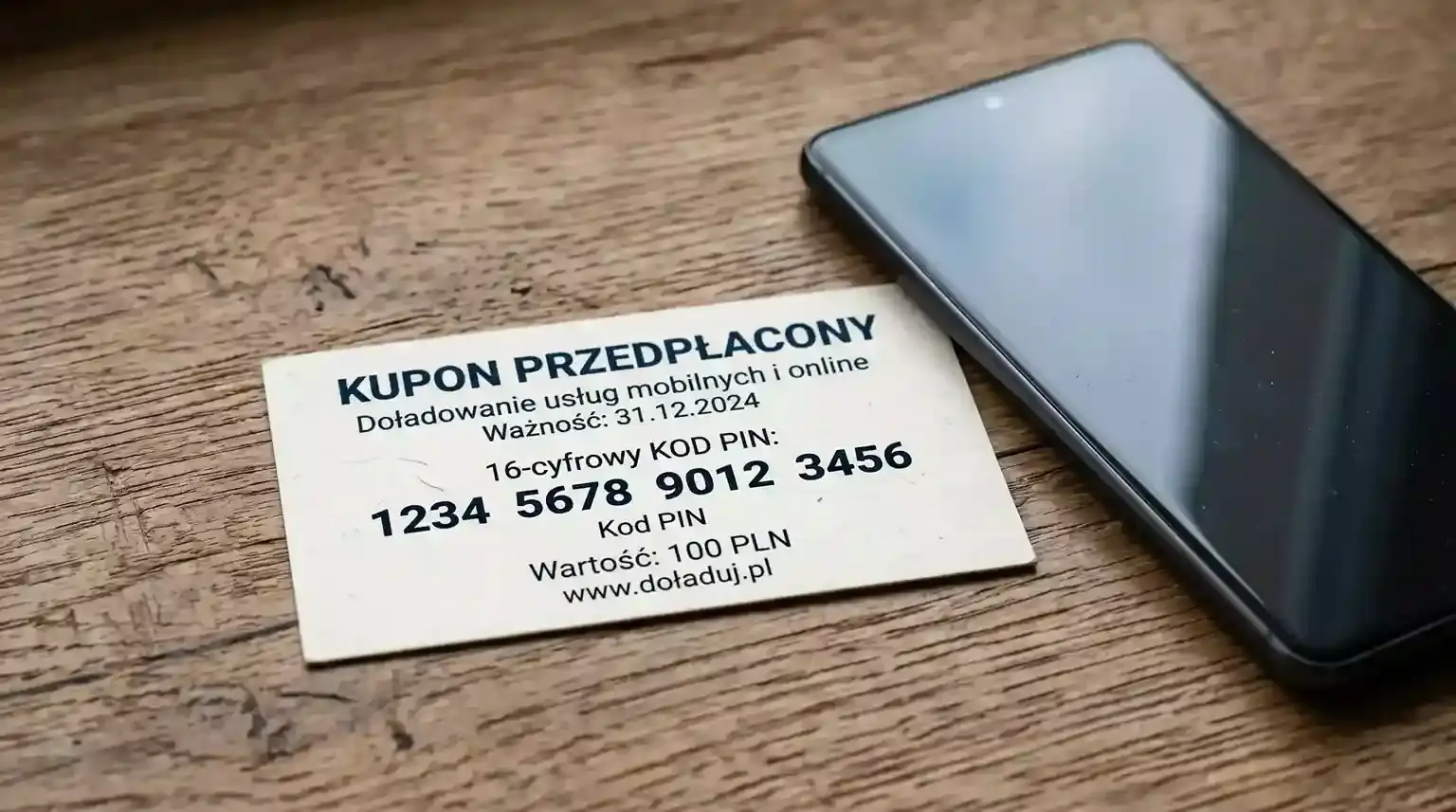 Kupon paysafecard z widocznym kodem PIN obok smartfona z aplikacją bukmachera