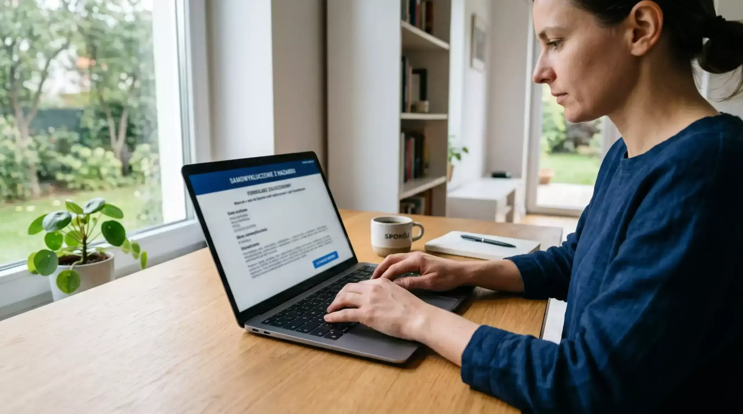 Osoba przy biurku wypełniająca formularz samowykluczenia z hazardu na laptopie